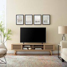 a living room scene with focus on the entertainment center and chair, which has three framed pictures on the wall