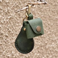 a green leather keychain hanging from a tree branch