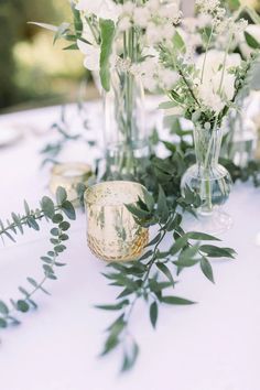 white flowers and greenery in vases on a table