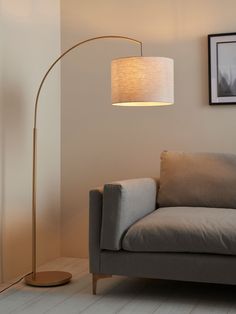 a living room with a couch, lamp and pictures hanging on the wall above it