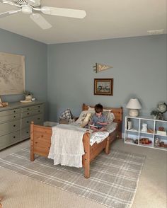 a young boy sitting on his bed reading a book