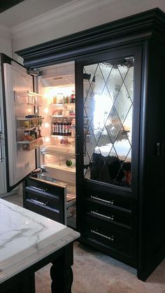 an open refrigerator in a kitchen with marble counter tops and black cabinets on both sides