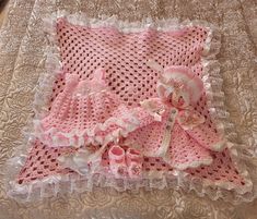 a crocheted blanket with pink and white ruffles on it sitting on top of a bed