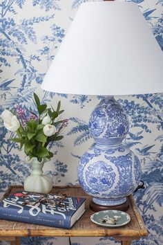 a blue and white vase sitting on top of a wooden table next to a lamp