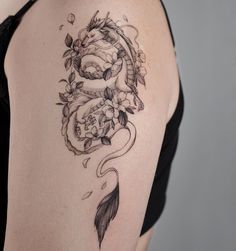 a woman with a tattoo on her shoulder has a dragon and flowers in the background