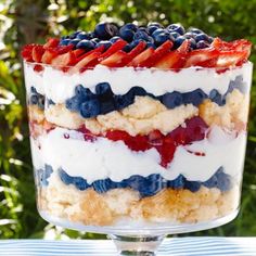 a trifle with strawberries, blueberries, and other toppings in a glass dish