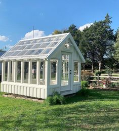 a small white house with a solar panel roof and windows on the side of it