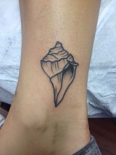 a small tattoo on the ankle of a woman's foot that has a seashell in it