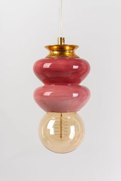 a red and pink light bulb hanging from a ceiling fixture with a gold top on it