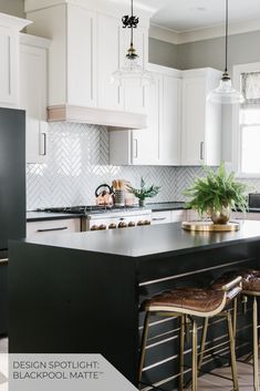 a kitchen with white cabinets and black countertops is pictured in this image, there are two stools at the center of the island