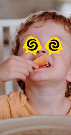 a child eating food with two yellow eyes