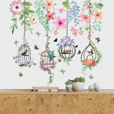 the wall is decorated with flowers and birdcages hanging from it's hooks