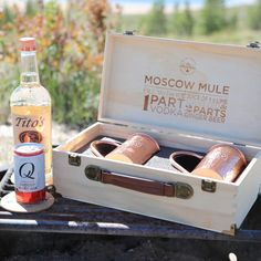 a bottle of alcohol sitting next to two wooden shoes on a grill with the lid open