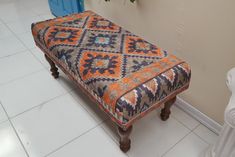 an orange and blue bench sitting on top of a tiled floor next to a plant