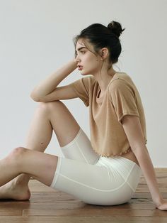 a woman sitting on the floor with her legs crossed wearing white tights and heels