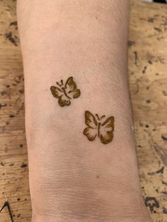 two small butterflies on the left wrist and right arm, one is brown with black spots