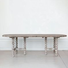 a wooden table sitting in the middle of a room next to a white wall and floor