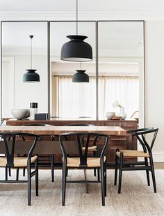 a dining room table with four chairs and a large mirror in the wall above it