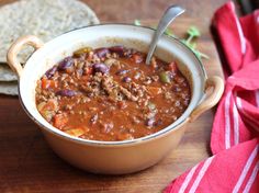 a bowl of chili and tortilla bread on a wooden table