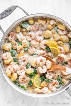 a pan filled with shrimp, potatoes and spinach