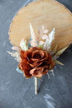 a boutonniere with dried flowers and leaves on a gray tablecloth background