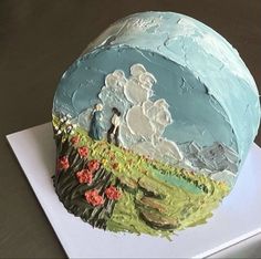 a cake that is sitting on top of a white paper plate with blue and green frosting