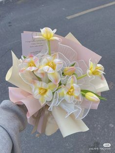 a person holding a bouquet of flowers with a card attached to the back of it