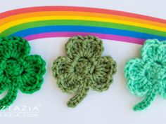 three crocheted shamrocks sitting next to each other on top of a rainbow