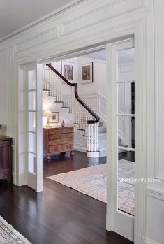 an open door leading to a living room with hardwood flooring and white painted walls