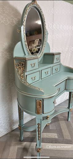 a blue vanity with a mirror on top and gold trim around the edges, in front of a white wall