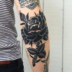 a woman's arm with black roses on it and an arrow in the middle