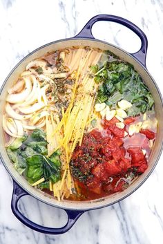 a pot filled with pasta and vegetables on top of a marble countertop next to a knife