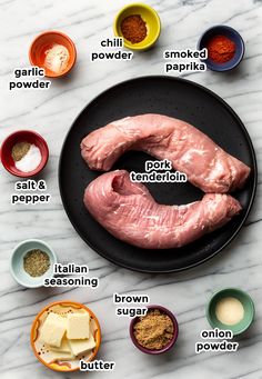 ingredients to make an uncooked chicken breast on a black plate with white marble counter top