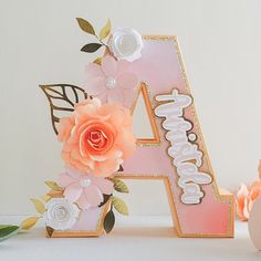 a pink and gold birthday cake with flowers on it's top, next to the number four