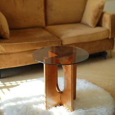 a glass table sitting on top of a white rug in front of a brown couch