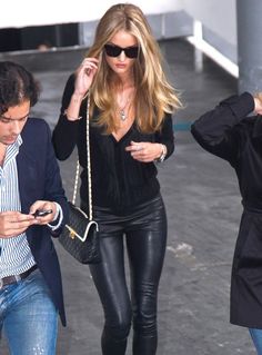 a woman walking down the street while looking at her cell phone and holding a purse