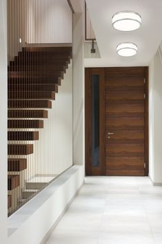 an empty hallway with stairs leading up to the door and light fixture on the ceiling