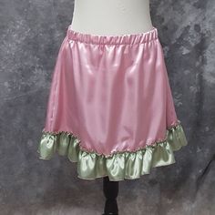 "Super cute and flirty A-line mini skirt made from Rose Pink poly satin with a ruffled bottom in Sage Green poly satin. This is a one of a kind item (OOAK) as I only had enough of each fabrics to make the one skirt. Size Large, elastic waist will fit waists from 34-39 inches (86.5-99 cm) . 18 inches in length BLOUSE AND WAIST CINCHER ARE NOT INCLUDED. THIS IS A FINISHED ITEM AND WILL SHIP WITHIN 48 HOURS OF COMPLETED PAYMENT. ✿This piece will be handmade entirely by me from design to completion Fairy Kei Mini Skirt With Ruffles, Fairy Kei Fitted Mini Skirt, Fitted Mini Skirt In Fairy Kei Style, Pink Fairy Kei Mini Skirt, Fairy Kei Pink Tiered Skirt, Pink Fairy Kei Tiered Skirt, Pink Skirted Petticoat With Ruffled Skirt, Pink Fitted Skirt For Cosplay, Fitted Pink Skirt For Cosplay