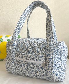 a blue and white floral purse sitting on top of a bed