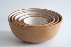 five brown and white bowls stacked on top of each other in front of a white background