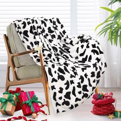 a cow print blanket sitting on top of a chair next to presents