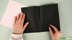 a person is holding an open book with their hands on top of it and touching the pages