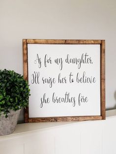 a wooden sign that says as for my daughter, i'll raise her to believe she breathes fire