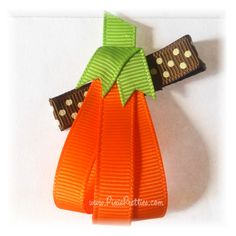 an orange and green bow with polka dots on the top is attached to a clip