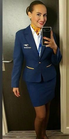 a woman in a blue suit taking a selfie with her cell phone while standing next to a door