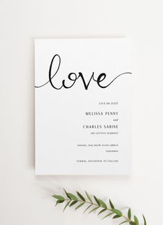 a white card with the word love written in black ink on it next to a plant