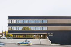 a police station building with cars passing by on the road in front and behind it