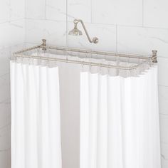 a white shower curtain hanging from the side of a bath tub