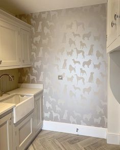 a kitchen with white cabinets and wallpaper that has dogs painted on the side of it