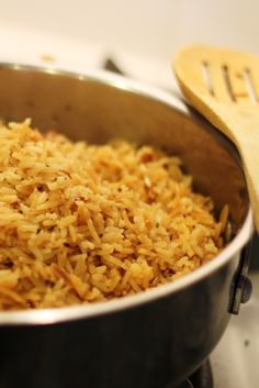 a pan filled with rice next to a wooden spoon